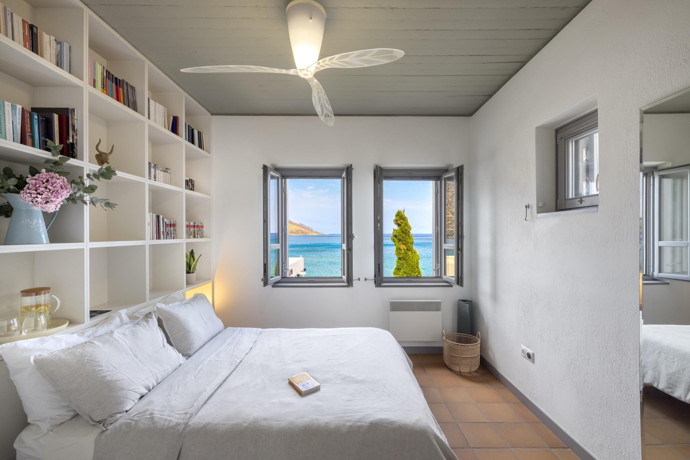 A bedroom with windows onto the sea