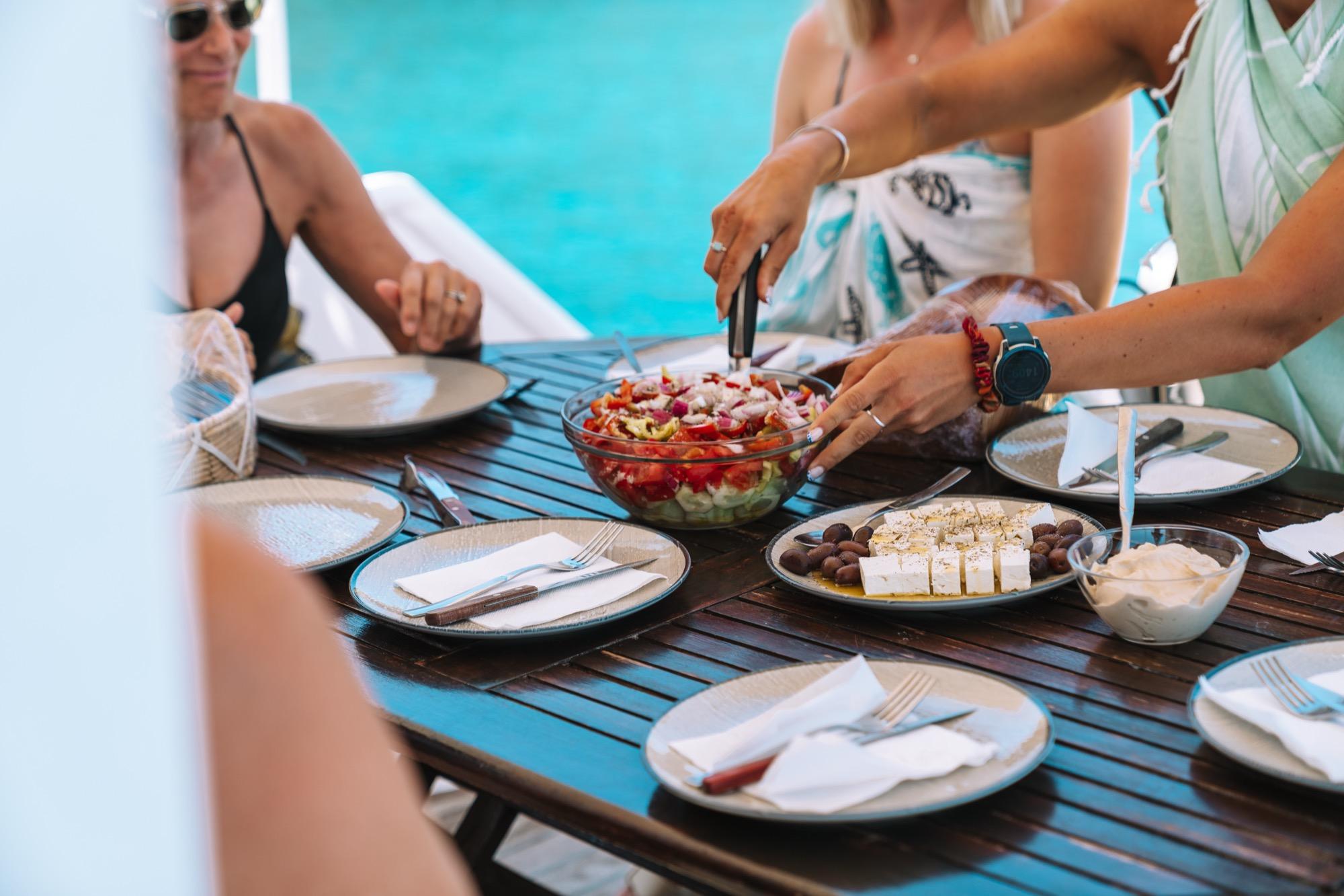 Hands sharing a salad at a table by the sea